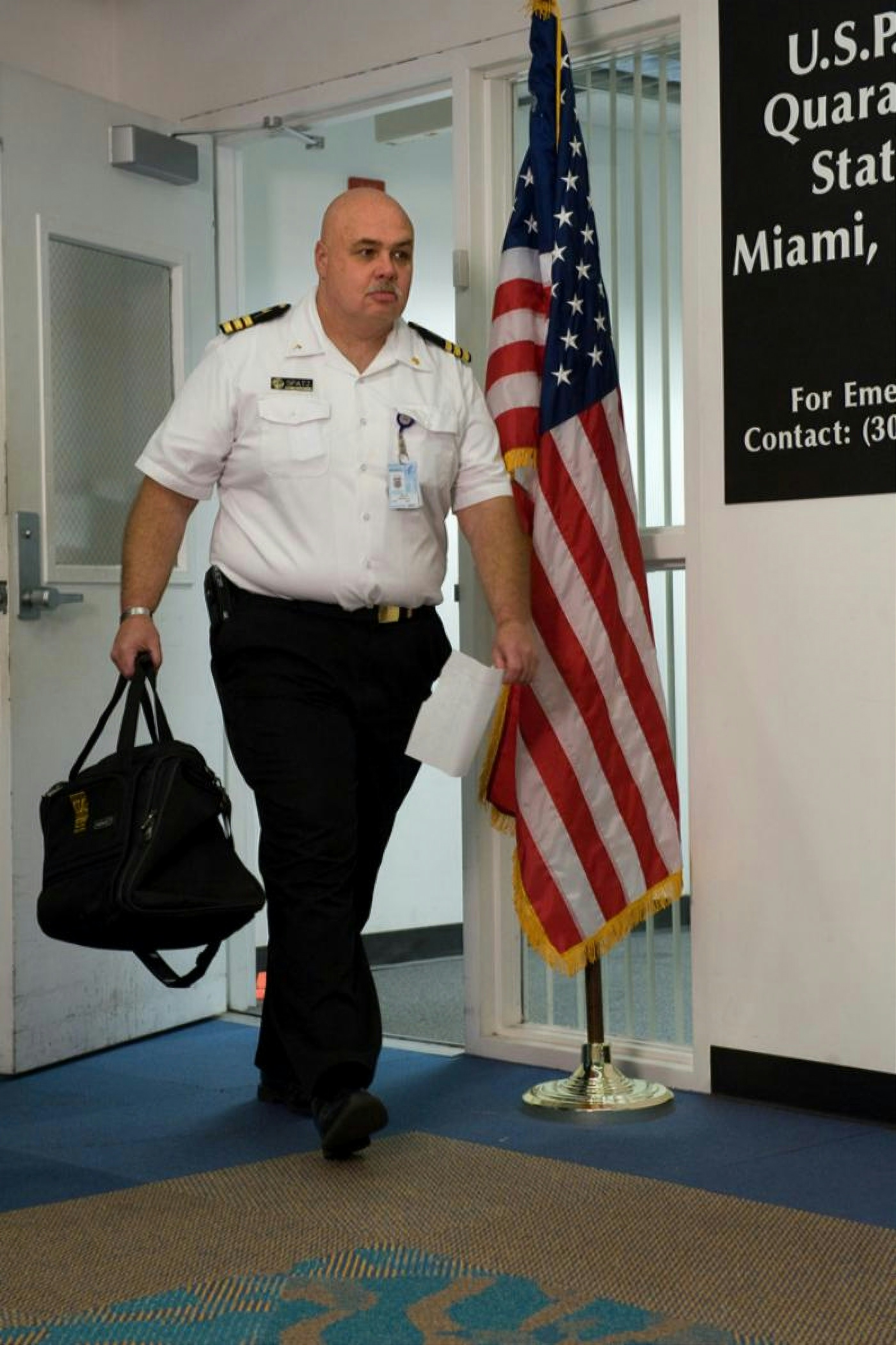 man in white button up shirt and black pants standing beside us flag